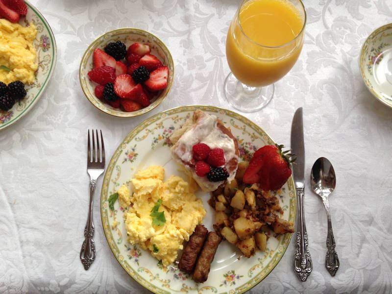 Gourmet breakfast plate with cinnamon roll, eggs and fresh fruit