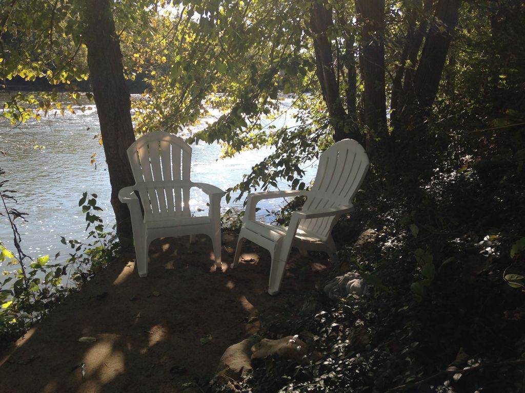 Riverside patio chairs under the trees